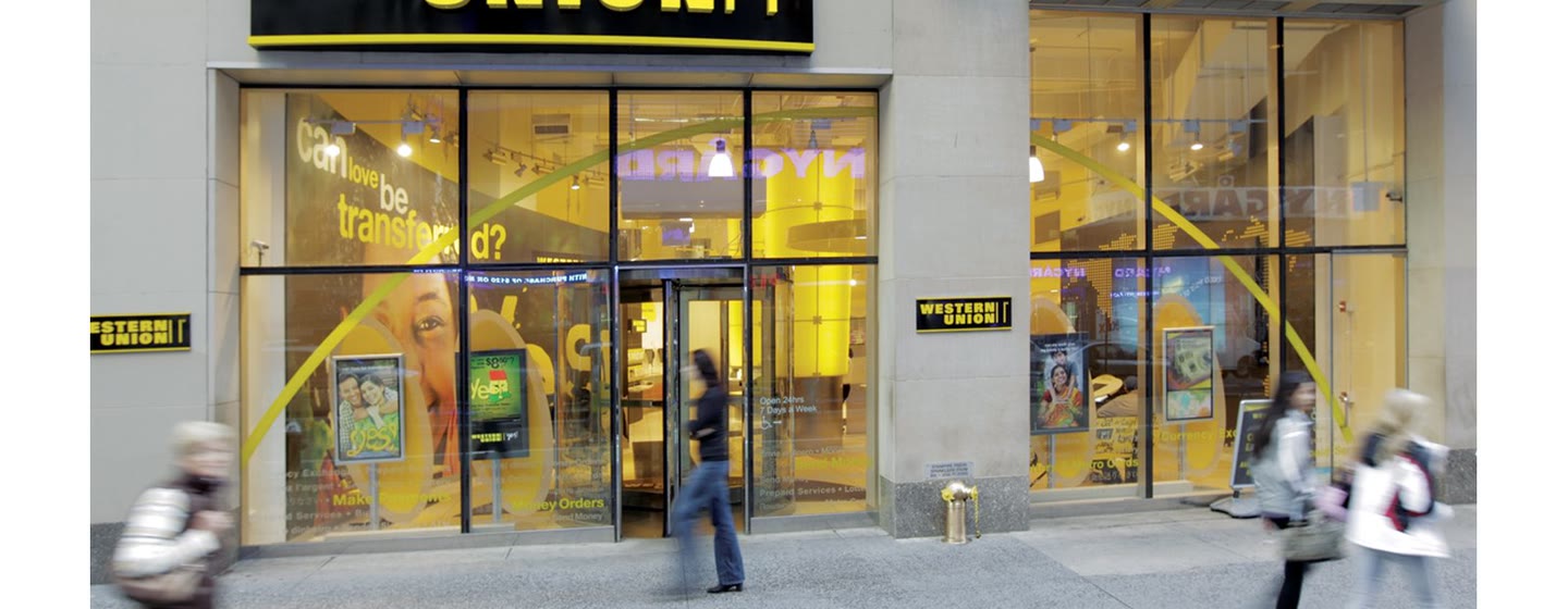 A Western Union agent storefront on Times Square, with people passing on the sidewalk